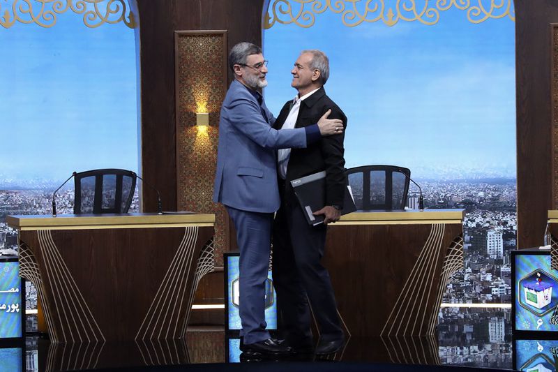 In this picture made available by Iranian state-run TV, IRIB, presidential candidate for the June 28 election Amirhossein Ghazizadeh Hashemi, left, embraces reformist candidate Masoud Pezeshkian after the conclusion of the candidates debate at the TV studio in Tehran, Iran, Tuesday, June 25, 2024. Iran's supreme leader Ayatollah Khamenei issued a thinly veiled warning Tuesday to the sole reformist candidate in the country's upcoming presidential election, saying anyone who believes "all ways to progress" come from the United States shouldn't be supported. (Morteza Fakhri Nezhad/IRIB via AP)