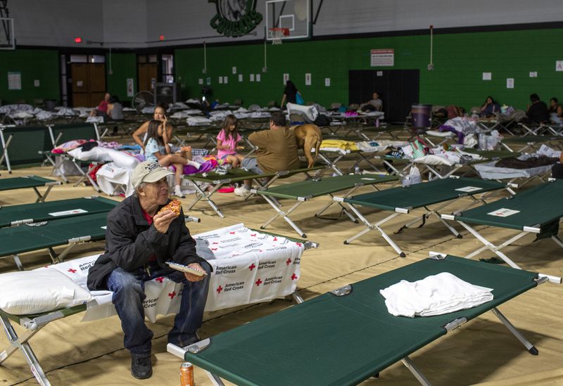 Steven Dobrovolskis eats a slice of pizza while spending the night at a shelter in Roswell, N.M., after evacuating from Ruidoso, Tuesday, June 18, 2024. Thousands of southern New Mexico residents fled the mountainous village as a wind-whipped wildfire tore through homes and other buildings. (AP Photo/Andres Leighton)