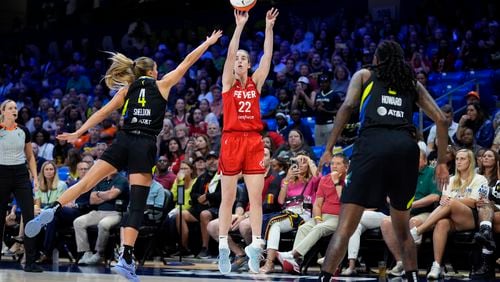 Indiana Fever guard Caitlin Clark (22) shoots as Dallas Wings' Jacy Sheldon (4) and Natasha Howard, right, defend in the first half of a WNBA basketball game Sunday, Sept. 1, 2024, in Arlington, Texas. (AP Photo/Tony Gutierrez)