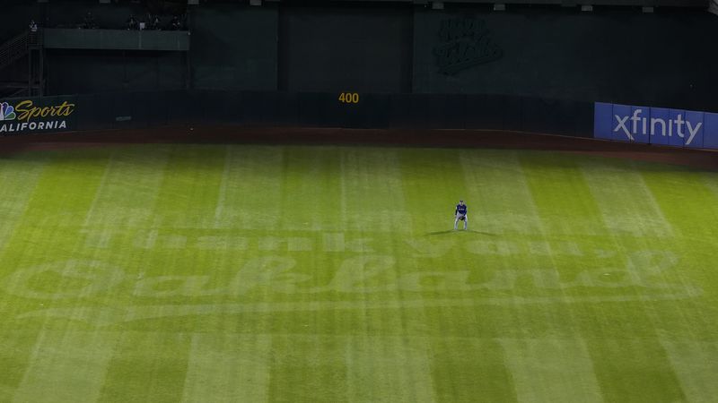 Texas Rangers center fielder Wyatt Langford stands over a message reading "Thank You Oakland" in the outfield grass during the third inning of a baseball game against the Oakland Athletics in Oakland, Calif., Wednesday, Sept. 25, 2024. (AP Photo/Jeff Chiu)