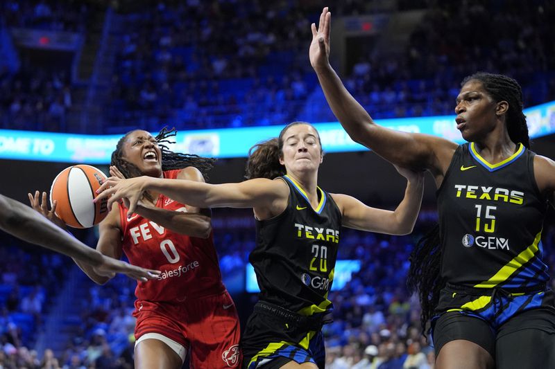 Indiana Fever guard Kelsey Mitchell (0) is fouled while shooting by Dallas Wings' Maddy Siegrist (20) as Wings center Teaira McCowan (15) helps defend in the first half of a WNBA basketball game Sunday, Sept. 1, 2024, in Arlington, Texas. (AP Photo/Tony Gutierrez)