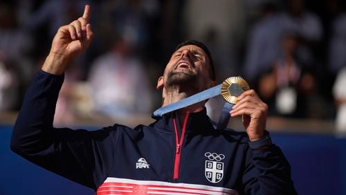 Serbia's Novak Djokovic shows his gold medal after defeating Spain's Carlos Alcaraz in the men's singles tennis final at the Roland Garros stadium during the 2024 Summer Olympics, Sunday, Aug. 4, 2024, in Paris, France. Djokovic has won his first Olympic gold medal by beating Alcaraz 7-6 (3), 7-6 (2) in the 2024 Games men's tennis singles final. (AP Photo/Louise Delmotte)