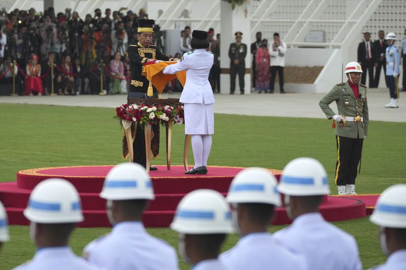 Indonesian President Joko Widodo, center left, hands national Red-White flag to a bearer to be hoisted during the ceremony marking Indonesia's 79th anniversary of independence at the new presidential palace in its future capital of Nusantara, a city still under construction on the island of Borneo, Saturday, Aug. 17, 2024. (AP Photo/Achmad Ibrahim)