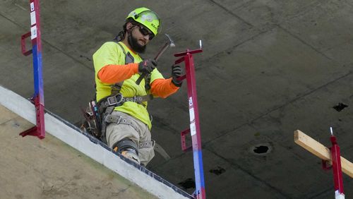 A construction worker installs a safety railing on a new building in Philadelphia, Tuesday, Sept. 3, 2024. (AP Photo/Matt Rourke)