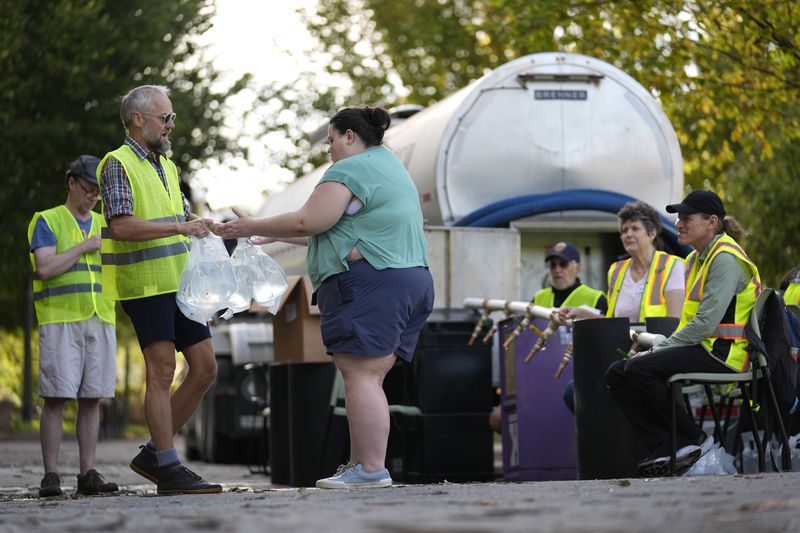 Workers hand out fresh water at a distribution site in the aftermath of Hurricane Helene Wednesday, Oct. 2, 2024, in Asheville, N.C. (AP Photo/Jeff Roberson)