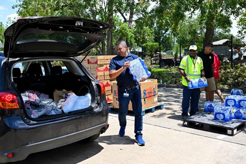 Volunteers hand out water at a distribution station in Houston, Wednesday, July 10, 2024. After Hurricane Beryl slammed into Texas, knocking out power to nearly 3 million homes and businesses. (AP Photo/Maria Lysaker)