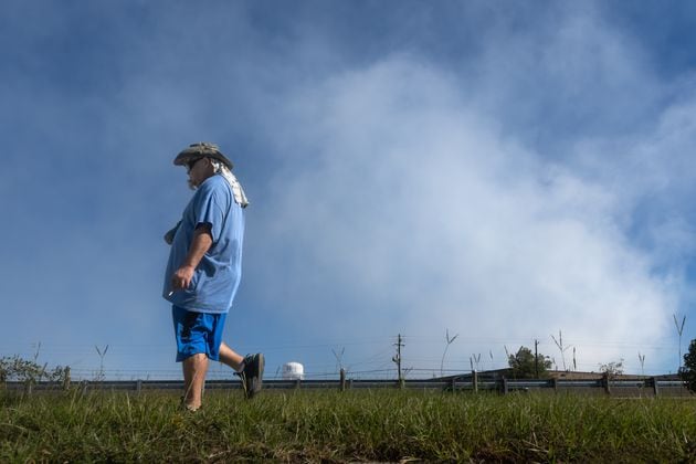 Darryl Shumake walks along Iris Drive at mid-morning Wednesday, Oct 2, 2024 as a large mile-long plume was still visible over Conyers as crews worked at the BioLab plant that caught on fire days earlier. But as the sun lifted above the horizon, so did the shelter-in-place order for Rockdale County residents. Those living nearby have been advised to stay inside every evening through early morning until Friday. (John Spink/AJC)