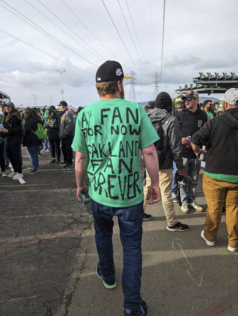 A fan wearing a shirt expressing his dismay with the A's move from Oakland while walking through the Oakland Coliseum parking lot on Opening Night, March 28, 2024, in Oakland, Calif. (AP Photo/Michael Liedtke)