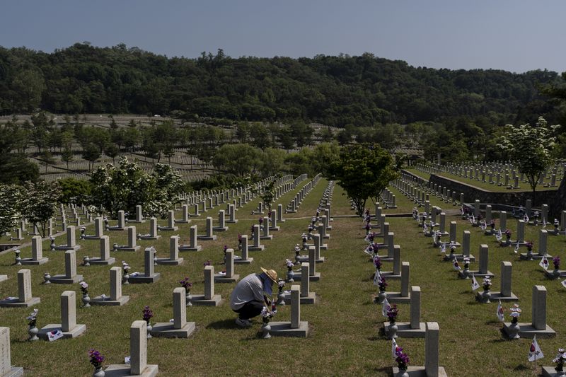 A worker places small South Korean flags at the graves of Korean soldiers who died in the Korean War ahead of Memorial Day at Seoul National Cemetery in Seoul, Thursday, May 23, 2024. (AP Photo/Jae C. Hong)