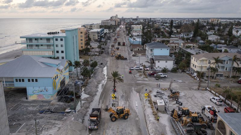 Crews work to clean up the tons of sand and debris pushed onto Gulf Boulevard from Hurricane Helene storm surge, Saturday, Sept. 28, 2024, in Madeira Beach, Fla. (Luis Santana/Tampa Bay Times via AP)