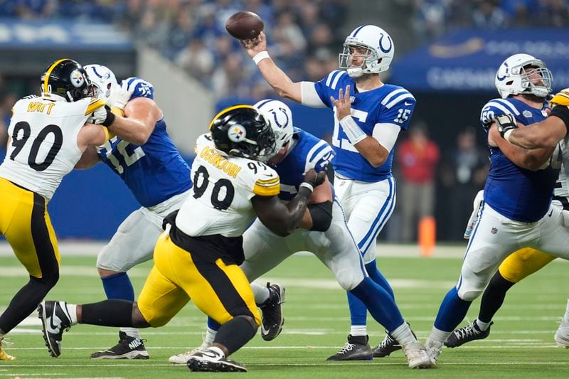 Indianapolis Colts quarterback Joe Flacco (15) throws a pass with Pittsburgh Steelers linebacker T.J. Watt (90) and defensive tackle Larry Ogunjobi (99) defending during the first half of an NFL football game Sunday, Sept. 29, 2024, in Indianapolis. (AP Photo/Michael Conroy)