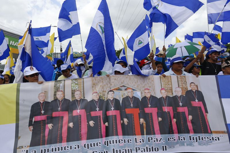 FILE - Anti-government demonstrators hold a banner featuring a group of Catholic cardinals including Nicaraguan Leopoldo Brenes, center right, and a quote from John Paul II that reads in Spanish, "The Church is the first to want peace!", during a march supporting the Catholic Church, in Managua, Nicaragua, July 28, 2018. (AP Photo/Alfredo Zuniga, File)