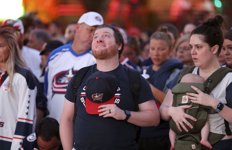 Columbus Blue Jackets fan Nathan Steele of Columbus, has a moment of silence during the candlelight vigil to honor Columbus Blue Jackets hockey player Johnny Gaudreau, outside of Nationwide Arena in Columbus, Ohio, Thursday, Sept. 4, 2024. Gaudreau and his brother Matthew were killed by a motor vehicle last week while riding bicycles. (AP Photo/Joe Maiorana)