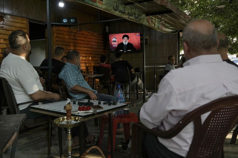 People listen to a speech by Hezbollah leader Sayyed Hassan Nasrallah broadcasted on Hezbollah's al-Manar television channel, at a coffee shop in a southern suburb of Beirut, Lebanon, Sunday, Aug. 25, 2024, hours after Israel and Hezbollah traded heavy fire. (AP Photo/Bilal Hussein)