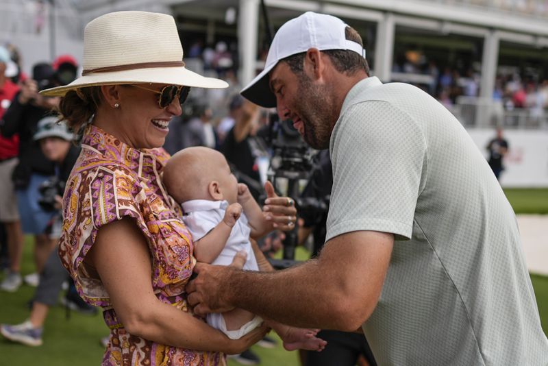 Scottie Scheffler holds his son Bennett Ezra Scheffler as his wife Meredith Scudder looks on on the 18th green after Scheffler won the final round of the Tour Championship golf tournament, Sunday, Sept. 1, 2024, in Atlanta. (AP Photo/Mike Stewart)