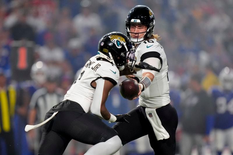 Jacksonville Jaguars quarterback Trevor Lawrence (16) hand off to running back Travis Etienne Jr. (1) during the first half of an NFL football game against the Buffalo Bills, Monday, Sept. 23, 2024, in Orchard Park, NY. (AP Photo/Steven Senne)