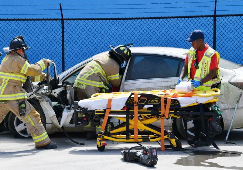 Female fire and EMS crew conduct a rescue simulation in font of participants during a “Females in the Fire Service” event at Dekalb County Fire Station 7 on Saturday, June 22, 2024 in Decatur.  (Hyosub Shin / AJC)