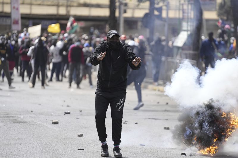 Protesters scatter as police fire teargas at them during a protest over proposed tax hikes in a finance bill in downtown Nairobi, Kenya Tuesday, June. 25, 2024. (AP Photo/Brian Inganga)