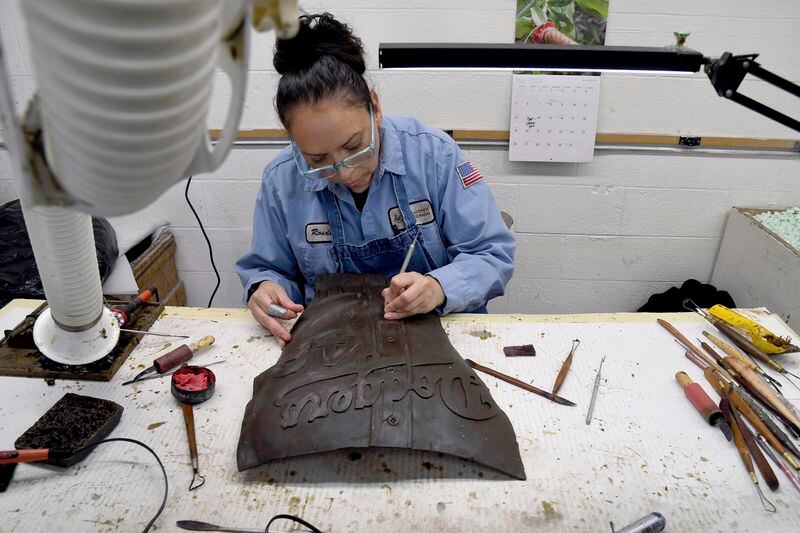 Rosalee Gonsalez, an employee at Art Castings of Colorado, touches up a wax mold of Jackie Robinson's jersey in Loveland, Colo. on Wednesday, May 8, 2024. The original statue was cut off at the ankles and stolen from a park in Wichita, Kansas in January. The Colorado foundry cast that sculpture in 2019 and, luckily, still had the original plaster and rubber molds. (AP Photo/Thomas Peipert)