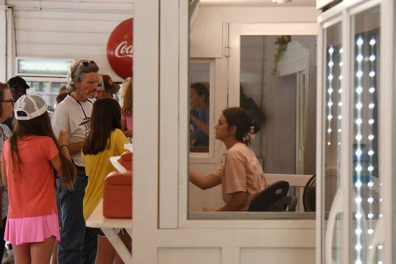 A Dickey Farms employee brings an order of soft serve to shop patrons on Wednesday, July 3, 2024, in Musella, Georgia. Dickey Farms is the oldest, continuously operating peach packinghouse in Georgia and offers tours and sells homemade goods and produce in their shop. (Photo Courtesy of Katie Tucker/The Telegraph)