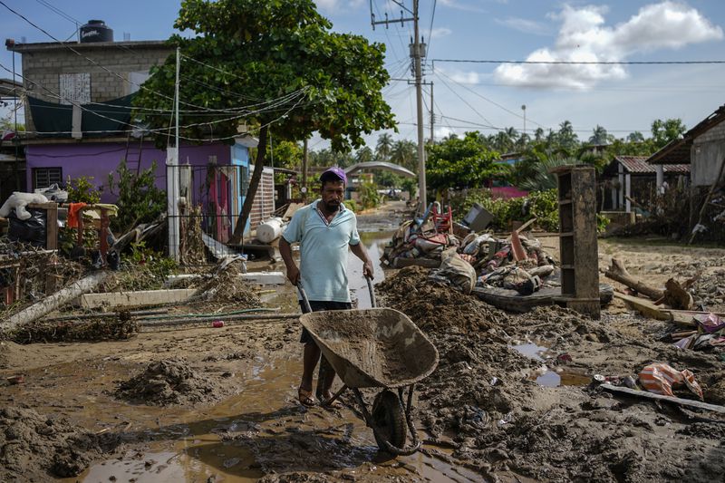 A man pushes a wheelbarrow through a damaged street after Hurricane John passed through Coyuca de Benitez, Guerrero state, Mexico, Monday, Sept. 30, 2024. (AP Photo/Felix Marquez)