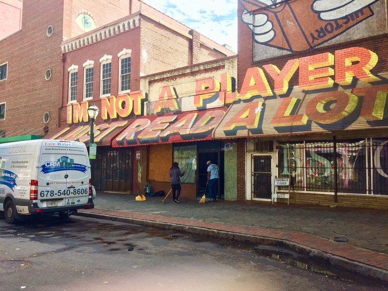 Cleanup crews get ready to board up windows at a building on Broad Street after an overnight shooting. Photo by Bill Torpy