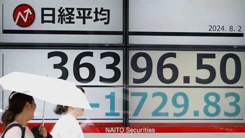 People pass by an electronic stock board in Tokyo Friday, Aug. 2, 2024. (Kyodo News via AP)