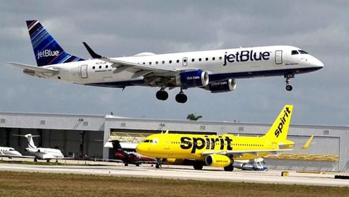 A JetBlue airliner lands past a Spirit Airlines jet on taxi way at Fort Lauderdale Hollywood International Airport on Monday, April 25, 2022. (Joe Cavaretta/Sun Sentinel/TNS)
