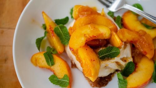 A mini peach jam-flavored pavlova topped with fresh peaches and zesty mint makes an elegant and easy summer dessert. (Virginia Willis for The Atlanta Journal-Constitution)