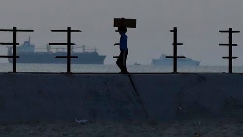 A Palestinian boy carries an aid box after storming trucks loaded with humanitarian aid brought in through a new U.S.-built pier, at the beach road of Nusseirat refugee camp, central Gaza Strip, Saturday, May 18, 2024. (AP Photo/Saher Alghorra)