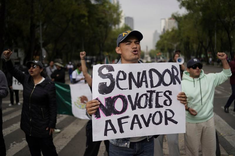 A protester holds a poster that reads in Spanish "Senator, don't vote in favor" against the judicial reform bill, outside the Senate in Mexico City, Thursday, Sept. 5, 2024, the day after Congress passed legislation that would require all judges to stand for election. (AP Photo/Felix Marquez)