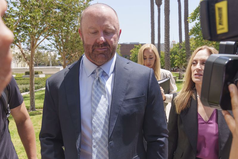 Mathew Bowyer, left, a Southern California bookbinder, arrives with his attorney, Diane Bass, right, in federal court in Santa Ana, Calif., Friday, Aug. 9, 2024. (AP Photo/Damian Dovarganes)