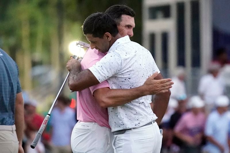 Aaron Rai, of England, front, is hugged by playing partner Billy Horschel, back, after winning the Wyndham Championship golf tournament in Greensboro, N.C., Sunday, Aug. 11, 2024. (AP Photo/Chuck Burton)