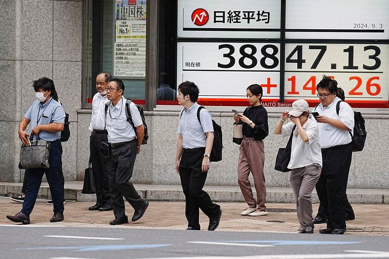 People walk in front of an electronic stock board showing Japan's Nikkei index at a securities firm Tuesday, Sept. 3, 2024, in Tokyo. (AP Photo/Eugene Hoshiko)