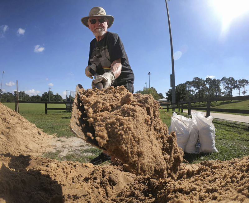 Denis Keeran, of Maitland, fills sandbags at the Orange County distribution site at Barnett Park in Orlando, Fla., Tuesday, Sept. 24, 2024, ahead of the forecast for the possibility of heavy rains in Central Florida. (Joe Burbank/Orlando Sentinel via AP)