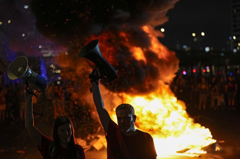 People block a road as they protest calling for a deal for immediate release of hostages held in the Gaza Strip by the Hamas militant group, in Tel Aviv, Sunday, Sept. 1, 2024. (AP Photo/Ariel Schalit)