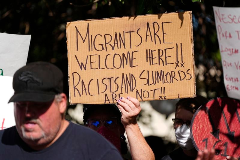 A protester holds up a placard during a rally staged by the East Colfax Community Collective to address chronic problems in the apartment buildings occupied by people displaced from their home countries in central and South America Tuesday, Sept. 3, 2024, in Aurora, Colo. (AP Photo/David Zalubowski)