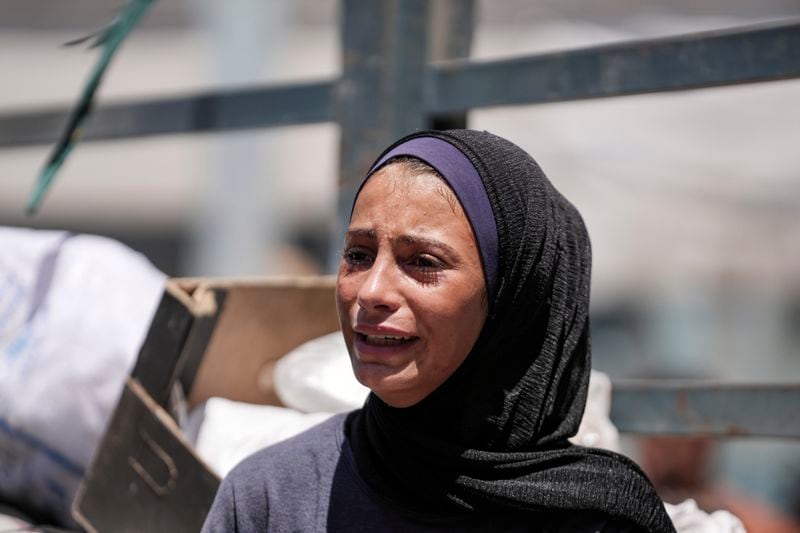 A Palestinian girl weeps on a truck as she evacuates a school that had been her shelter, in eastern Deir al-Balah, Gaza Strip, Friday, Aug. 16, 2024, after the Israeli military dropped leaflets asking civilians to evacuate from the area, saying forces plan to respond to rocket fire that targeted Israel. (AP Photo/Abdel Kareem Hana)