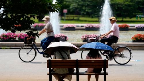 FILE - People holding parasols sit on the bench under an intense sun at a park in Tokyo, July 8, 2024. Japan’s total population marked the 15th straight year of decline, according to government data released Wednesday, July 24. (AP Photo/Eugene Hoshiko, File)