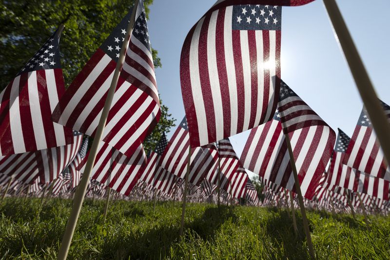 FILE - The sun shines through the flags in the Memorial Day Flag Garden on Boston Common, May 27, 2023, in Boston. Businesses increasingly have chosen to stay open on the holiday, leading to what is now one of the biggest retail sales and travel weekends of the year. (AP Photo/Michael Dwyer, File)