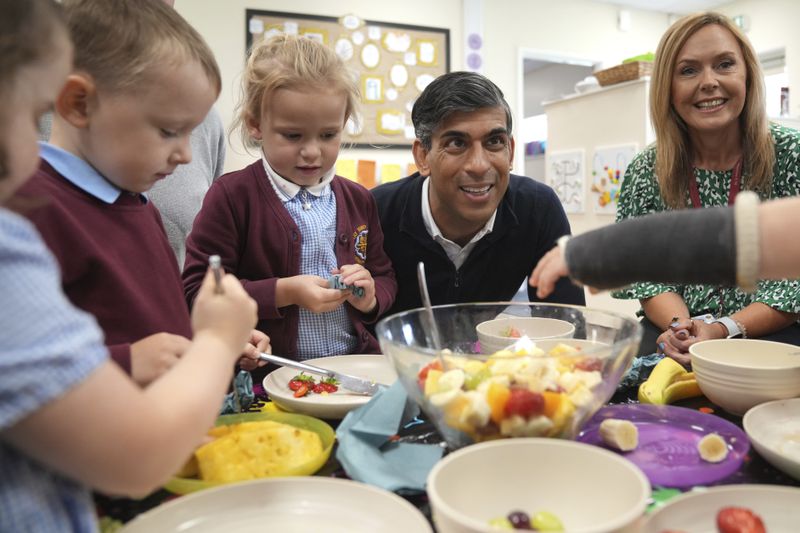 Britain's Prime Minister Rishi Sunak looks on as school children have some fruit during an election campaign visit to the Holy Trinity Rosehill CofE Primary school in Teeside, northeast England, Friday, June 28, 2024. (AP Photo/Kin Cheung, Pool)