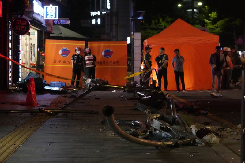 Rescuers stand near wreckage at the site of a car accident near Seoul City Hall in downtown Seoul, South Korea, Monday, July 1, 2024. A car hit pedestrians waiting at a traffic light in central Seoul on Monday evening, killing nine people and injuring four, South Korea's emergency officials said. (AP Photo/Ahn Young-joon)