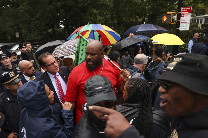 A protestor talks with law enforcement personnel and media while demonstrating against New York City Mayor Eric Adams during a news conference outside Gracie Mansion, Thursday, Sept. 26, 2024, in New York. (AP Photo/Yuki Iwamura)