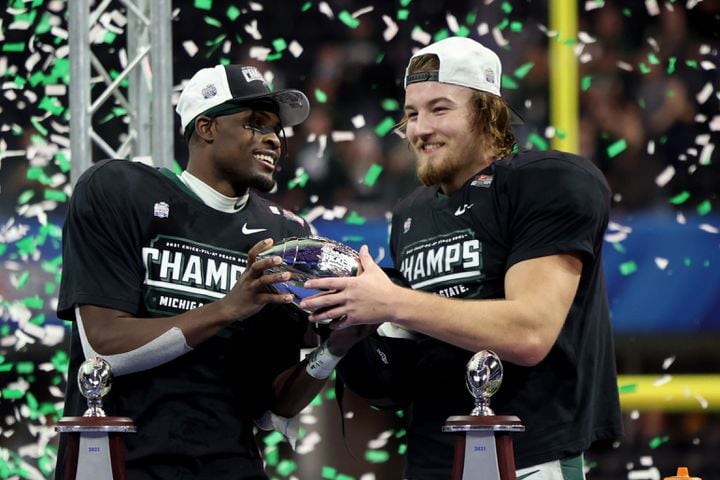 Michigan State Spartans wide receiver Jayden Reed, left, hands the trophy to linebacker Cal Haladay after their 31-21 win against the Pittsburgh Panthers during the Chick-fil-A Peach Bowl at Mercedes-Benz Stadium in Atlanta, Thursday, December 30, 2021. JASON GETZ FOR THE ATLANTA JOURNAL-CONSTITUTION