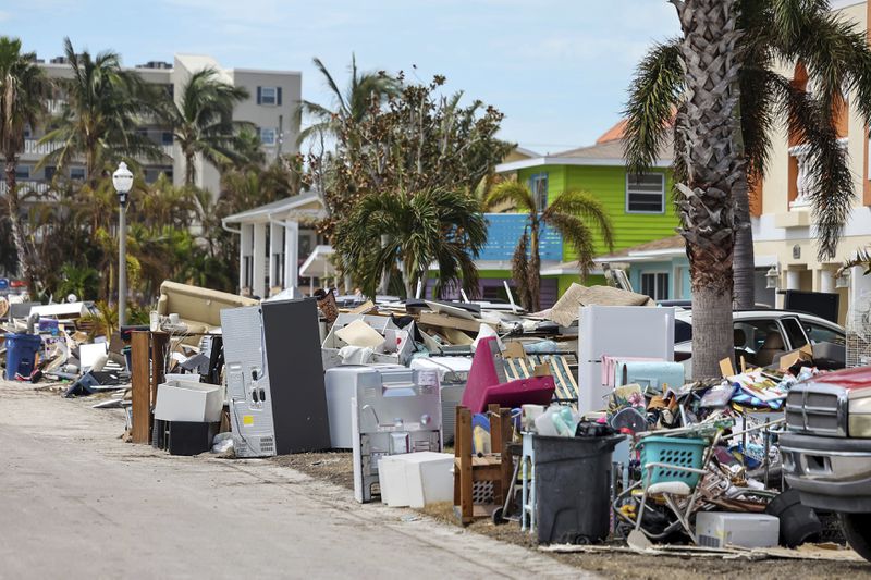 Contents of homes line the streets after flooding from Hurricane Helene on Wednesday, Oct. 2, 2024, in Reddington Shores, Fla. (AP Photo/Mike Carlson)