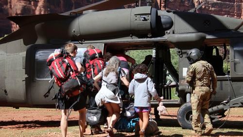 U.S. Army soldiers of the Arizona National Guard guide tourists trapped by flash flooding into a UH-60 Blackhawk, Saturday, Aug. 24, 2024, on the Havasupai Reservation in Supai, Ariz. (Maj. Erin Hannigan/U.S. Army via AP)