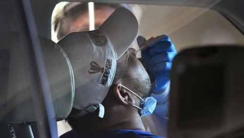 A medical professional collects a nasal swab from a potential COVID-19 patient at a drive-through COVID-19 testing site for anyone who is experiencing symptoms at the Infinite Energy Center in Duluth on Wednesday, April 22, 2020. The test can be uncomfortable because the nasal swab must travel far up the nose to capture a good sample. HYOSUB SHIN / HYOSUB.SHIN@AJC.COM