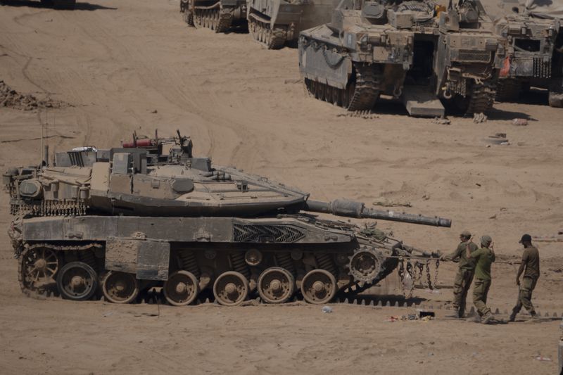 Israeli soldiers work on a tank in a staging area near the Israeli-Gaza border in southern Israel, Monday, June 3, 2024. (AP Photo/Leo Correa)