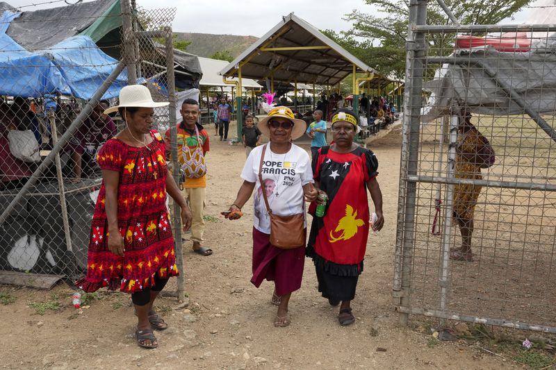 A woman, center, wears a shirt with a photo of Pope Francis at a market ahead of his visit to Port Moresby, Papua New Guinea, Friday, Sept. 6, 2024. (AP Photo/Mark Baker)