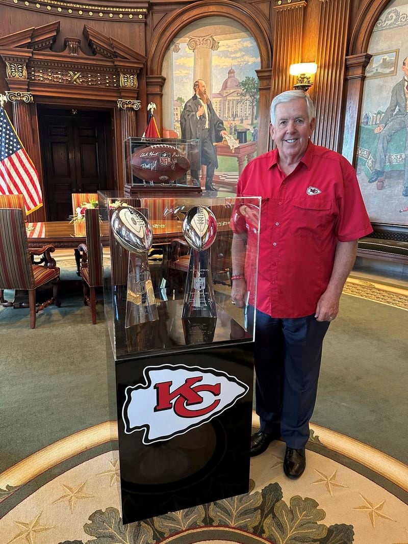 Missouri Gov. Mike Parson poses next to the Kansas City Chiefs' two most recent Super Bowl trophies on display in his Capitol office in Jefferson City, Mo., Thursday, June 27, 2024. Parson said Missouri is working on a public aid proposal for new or improved stadiums for Chiefs and Kansas City Royals. (AP Photo/David A. Lieb)